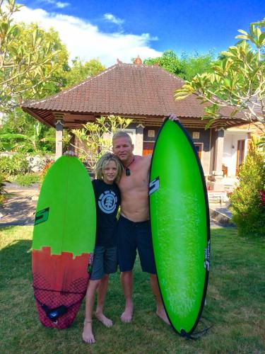 a man and a woman standing next to surfboards at UmahOde Bali in Nusa Dua
