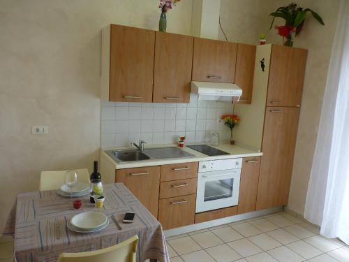 uma cozinha com armários de madeira, um lavatório e uma mesa em Residence Costablu em Rimini