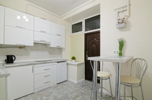 リヴィウにあるApartment - Medova 9の白いキャビネット、テーブルと椅子付きのキッチンが備わります。