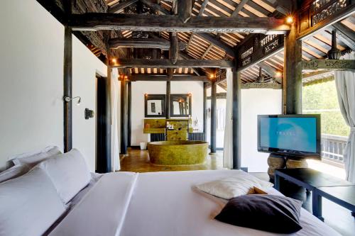 a bedroom with a bed with a television and a tub at Chen Sea Resort & Spa Phu Quoc in Phu Quoc