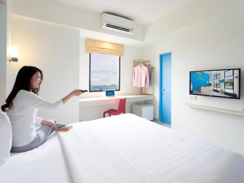 a woman is sitting on a bed in a hotel room at HOP INN Khon Kaen Srichan Road Building A in Khon Kaen