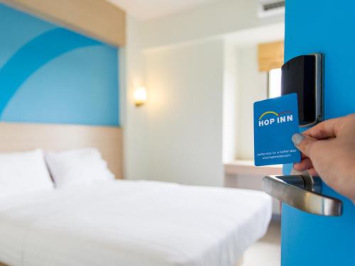 a person holding a hot inn card in a hotel room at HOP INN Khon Kaen Srichan Road Building A in Khon Kaen