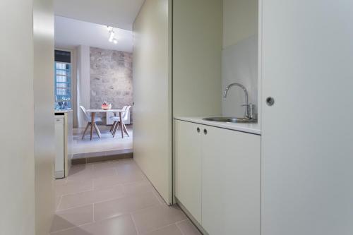 a kitchen with white cabinets and a sink and a table at Bravissimo Cort Reial-1B in Girona