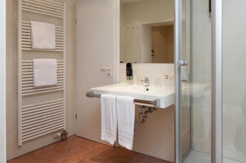 uma casa de banho com um lavatório e um chuveiro em Centro Hotel Mondial em Munique