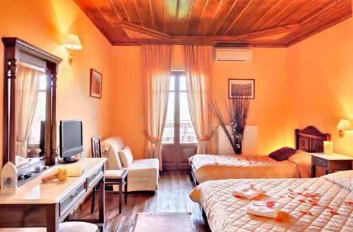a hotel room with two beds and a desk with a television at Konitsa Mountain Hotel in Konitsa