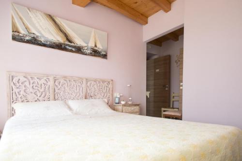 a bedroom with a large white bed with a painting on the wall at La Casa Sul Sasso in Dervio