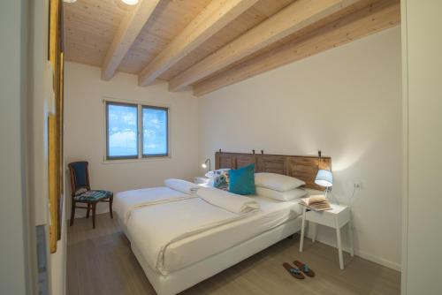 1 dormitorio con 1 cama blanca grande y 1 silla en La Gazza Ladra Apartments - Garda Chill Out, en Drena