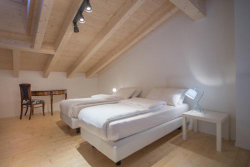 a white bedroom with a bed and a chair at La Gazza Ladra Apartments - Garda Chill Out in Drena