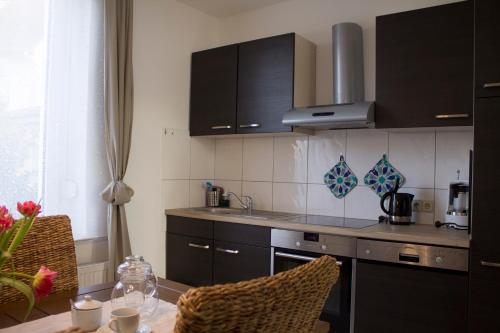 eine Küche mit schwarzen Schränken, einem Tisch und einer Arbeitsplatte in der Unterkunft Ferienwohnung Ohligs in Solingen