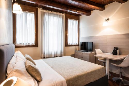 Habitación de hotel con cama, escritorio y TV. en MyPlace Padova Centro Storico en Padua