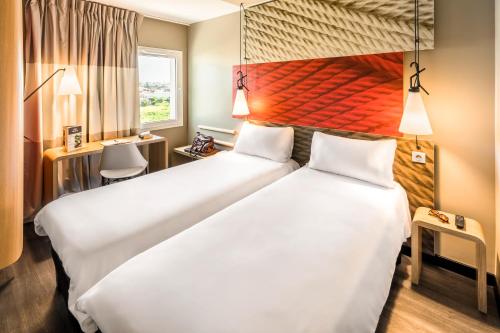 a hotel room with two beds and a window at Hotel ibis Faro Algarve in Faro