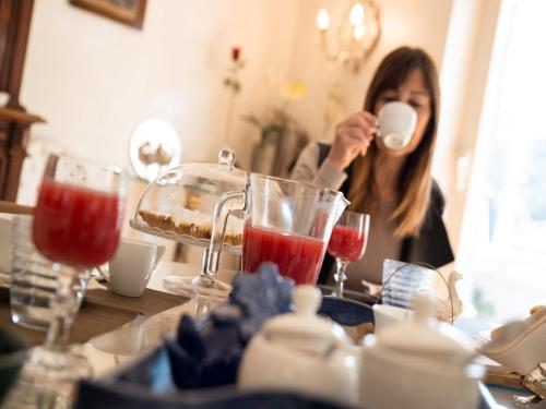 a woman sitting at a table drinking from a cup at Casa Malena in Ascoli Piceno