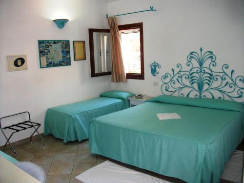 a room with two beds and a window at Hotel Villa Gemella in Baja Sardinia