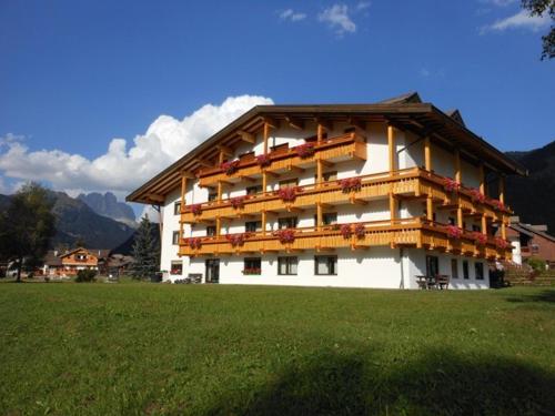 a large building with balconies on a green field at Residence Dolomia in Pozza di Fassa