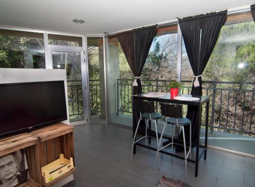 a living room with a television and a balcony at Les Suites in Santa María de Palautordera