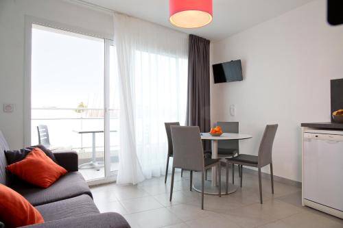 a living room with a couch and a table with chairs at Résidence Coté Mer in La Grande-Motte