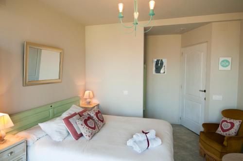 a bedroom with a white bed with pillows and a chandelier at Les Suites in Santa María de Palautordera