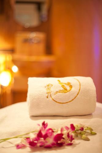 a white towel with a logo on it next to flowers at Broadway Hotel in Dubai