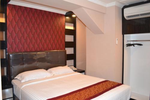 a bedroom with a bed with a red headboard at Puncak Budget Hotel in Pangkalpinang