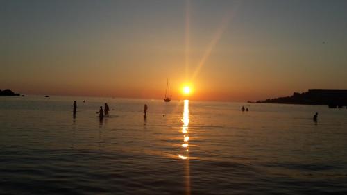 a group of people in the water at sunset at Mandalay in Mellieħa