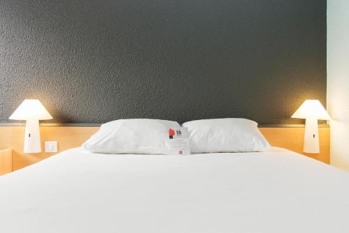 a bed with two white pillows and two lamps at ibis Falaise Coeur de Normandie in Falaise