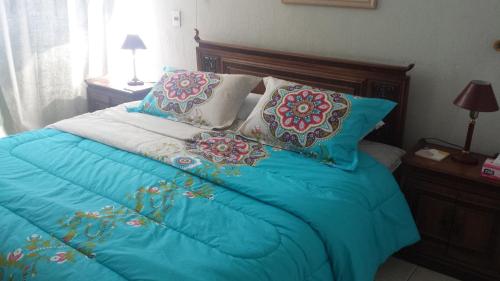 a bed with a blue comforter and pillows at Departamento Playa Amarilla Con Con in Concón