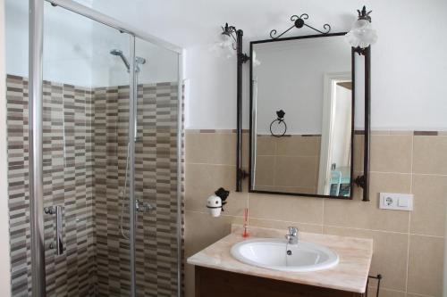 uma casa de banho com um lavatório e um chuveiro com um espelho. em La Fuente De El Nacimiento em Benamahoma
