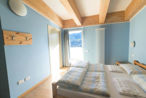 a bedroom with two beds and a large window at Hostel L'Ost - Ostello di Grumes in Grumes