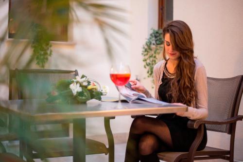 a woman sitting at a table with a glass of wine at Hotel Centrale Spa & Relax in Alcamo
