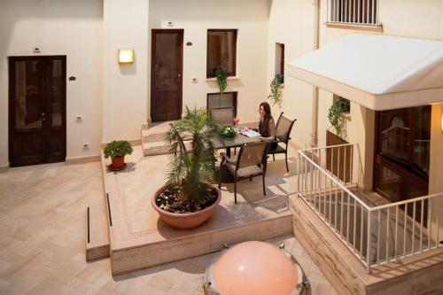 a woman sitting at a table in a room at Hotel Centrale Spa & Relax in Alcamo