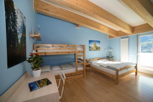 a bedroom with two bunk beds and a desk at Hostel L'Ost - Ostello di Grumes in Grumes