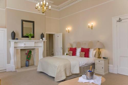 um quarto com uma cama branca com almofadas vermelhas e uma lareira em The Cheltenham Townhouse Studios at GLENFALL LAWN PITTVILLE CIRCUS em Cheltenham