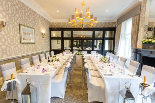 a room with white tables and white chairs and a chandelier at Trout Hotel in Cockermouth