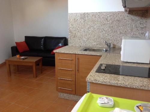 a kitchen with a sink and a couch in a room at Curral de l Tiu Pino in Sendim