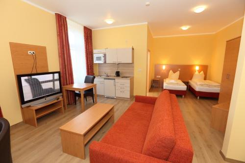 ein Wohnzimmer mit einem Sofa, einem Bett und einem TV in der Unterkunft Appartementhotel in Stade in Stade