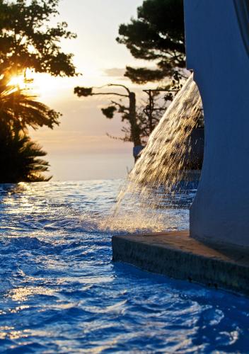 a fountain in the water with the sunset in the background at Hotel Orsa Maggiore in Anacapri