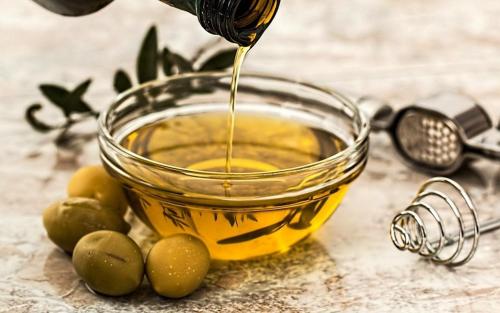 a glass bowl filled with oil next to green olives at Curral de l Tiu Pino in Sendim