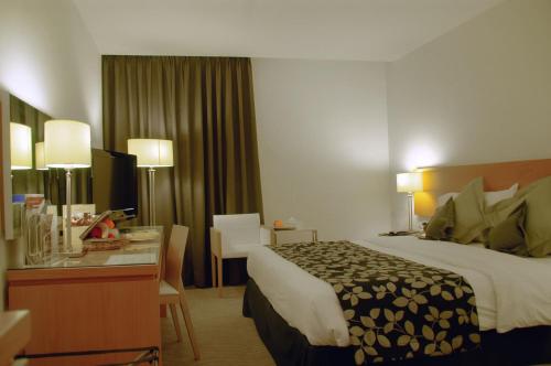 a hotel room with a bed and a desk at Amman Airport Hotel in Al Qasţal