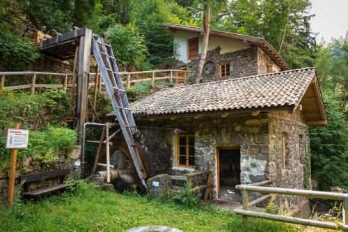 a small stone house with a ladder next to it at Hostel L'Ost - Ostello di Grumes in Grumes