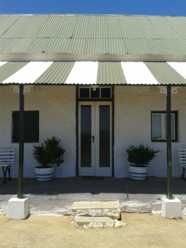 a white building with a green roof and a door at Silwerkaroo Gastehuis in Beaufort West