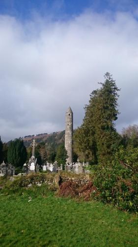 a cemetery with a tower in the middle of a field at The Glendalough Hotel in Laragh