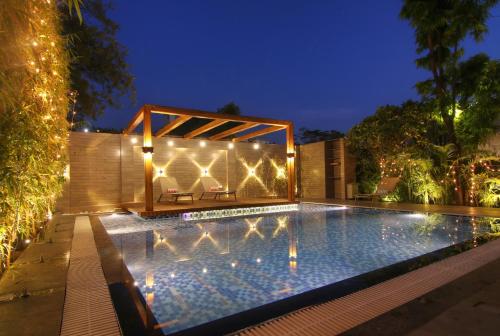 a swimming pool with lights in a backyard at night at Devraj Niwas in Jaipur