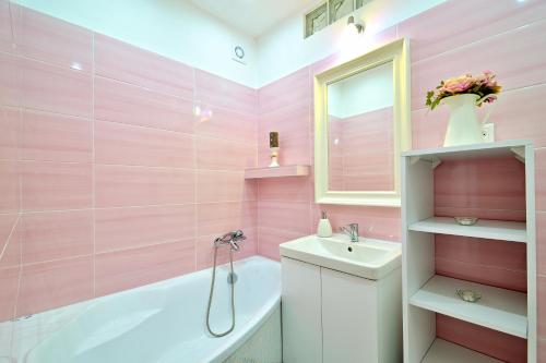 een roze badkamer met een bad, een wastafel en een bad bij Apartmán pod Kalváriou in Banská Štiavnica