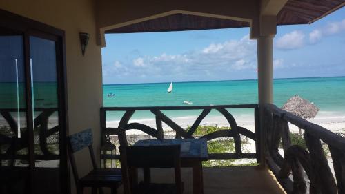 a balcony with a view of the beach and a sailboat at White Sands in Paje