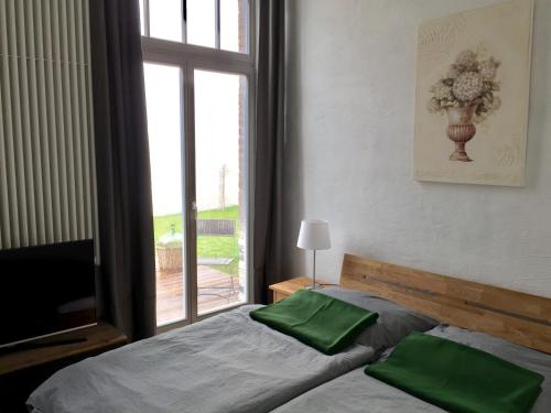 ein Schlafzimmer mit einem Bett mit grünen Kissen und einem Fenster in der Unterkunft Ferienwohnungen auf der Insel am Cafe Jacob in Werder