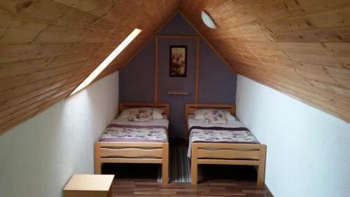 two beds in a attic room with wooden ceilings at Guest House Wolf in Jezerce