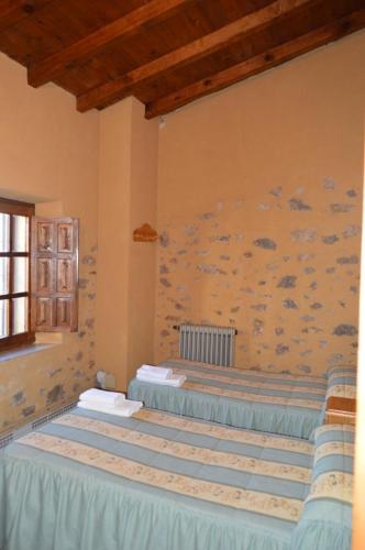 two beds in a room with a wall at Casa Rural La Vallejera in Tejeda de Tiétar