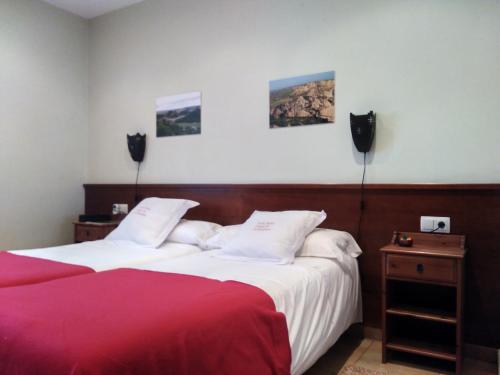 um quarto de hotel com duas camas com lençóis vermelhos e brancos em Camino de las Bardenas em Arguedas
