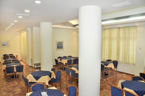 a room with tables and chairs in a room with columns at Hotel Elena in Lamía