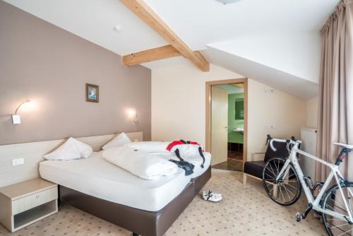 a bedroom with a bed and a bike in a room at Hotel Weingarten in Caldaro